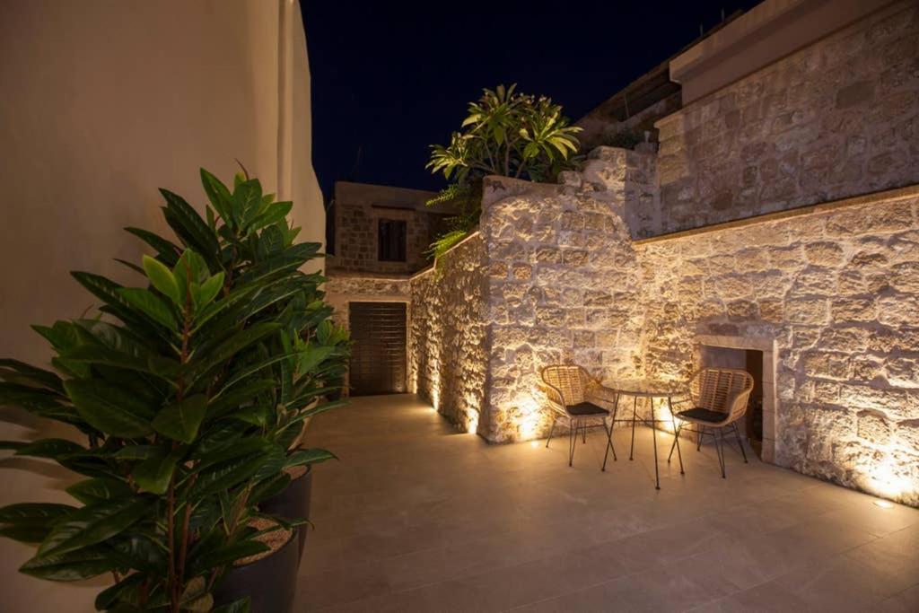 eine Terrasse mit einem Tisch und Stühlen neben einer Steinmauer in der Unterkunft Casa Quindici in the Old Town in Rhodos (Stadt)