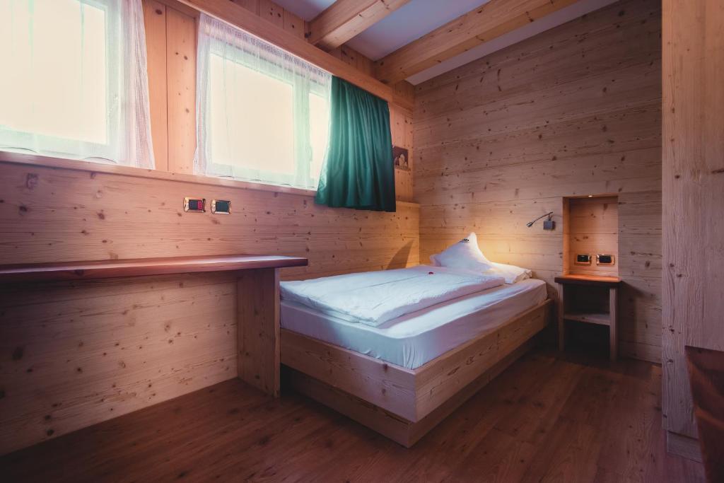 a bedroom with a bed in a wooden cabin at Hotel Zirmes in Moena
