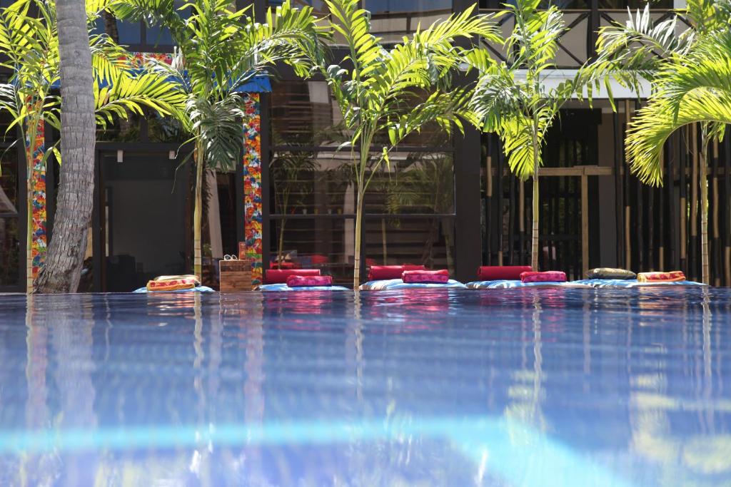 a swimming pool with palm trees in front of a building at Chaykovski Boutique H in Las Terrenas