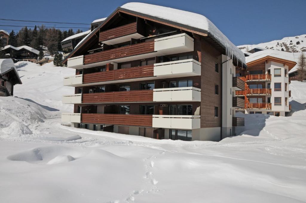 a building in the snow with snow around it at Alpenhaus Bettmeralp in Bettmeralp