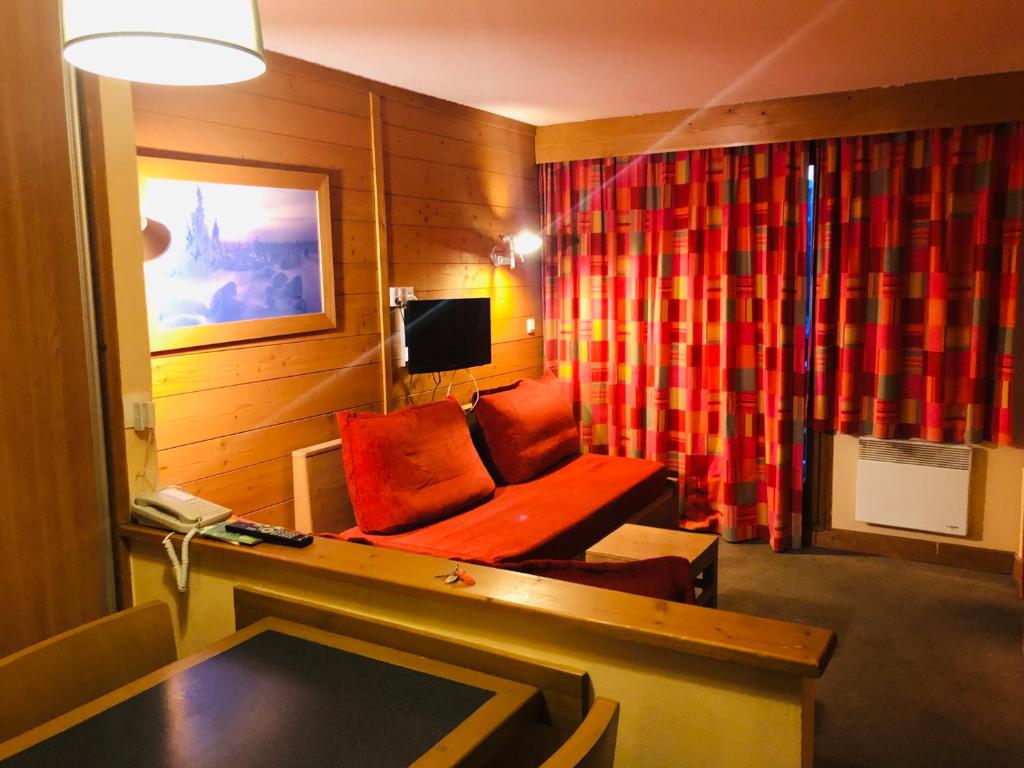 ein Wohnzimmer mit einem roten Stuhl und einem Sofa in der Unterkunft Appartement cozy centre Alpe d'Huez in L'Alpe-d'Huez