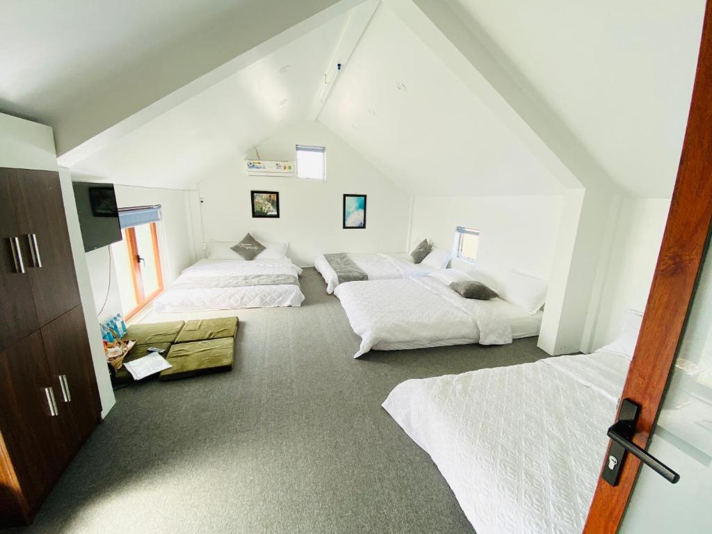 two beds in a room with white walls at RiverView HomeStay in Dong Hoi