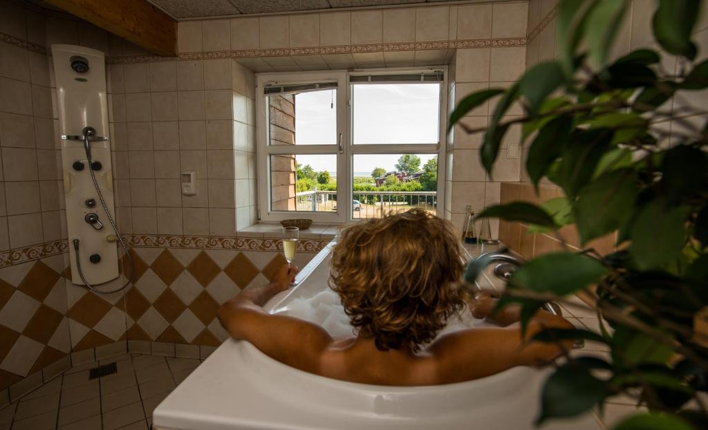 un uomo seduto in una vasca da bagno in bagno di Hotel Kommandørgården a Rømø Kirkeby