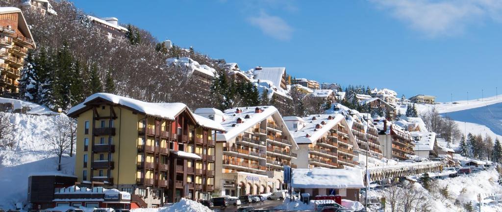 un hotel en una montaña nevada con edificios cubiertos de nieve en Appartamenti i Portici, en Prato Nevoso