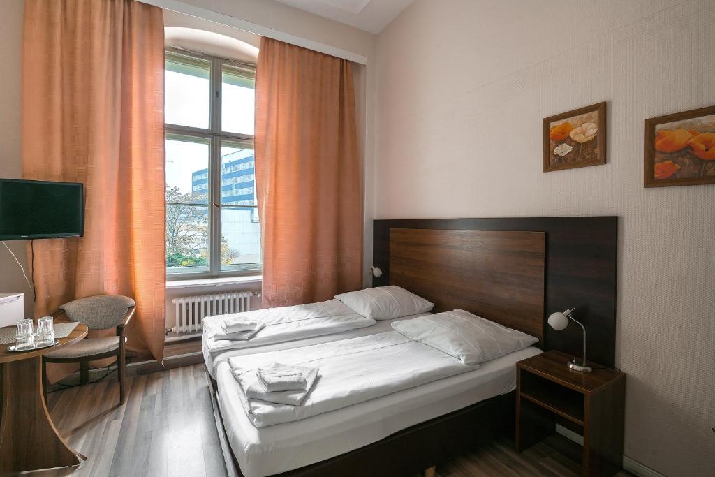 a bedroom with a bed and a desk and a window at Pension Classic in Berlin