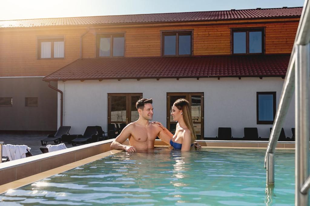 un hombre y una mujer sentados en una piscina en Barrico Thermal Hotel en Demjén