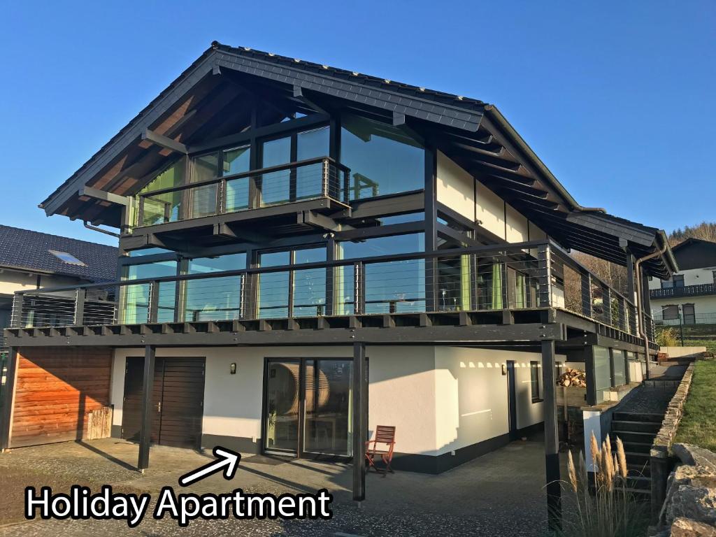een huis met een balkon en een bord met vakantieappartement bij Hunsrück Valley View Apartment with Cedar SAUNA in Bruschied