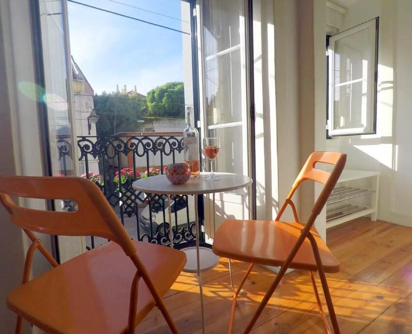 a table and chairs on a balcony with a glass of wine at Tram House @ Lx Factory! in Lisbon