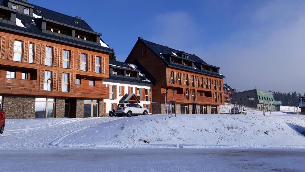 parking pokryty śniegiem przed niektórymi budynkami w obiekcie Apartman M5 Horní Mísečky w mieście Horni Misecky