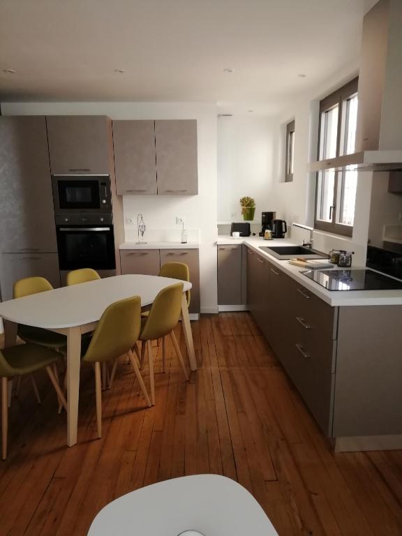 une cuisine avec une table blanche et des chaises dans l'établissement La Citadine maison de ville avec garage, à Bagnères-de-Bigorre