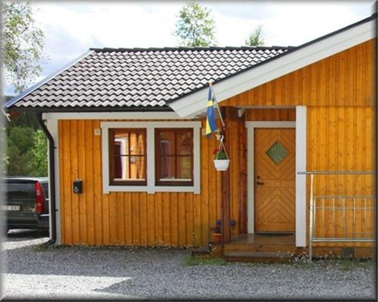una pequeña casa de madera con puerta y bandera en Funäsdalens Stugby en Funäsdalen