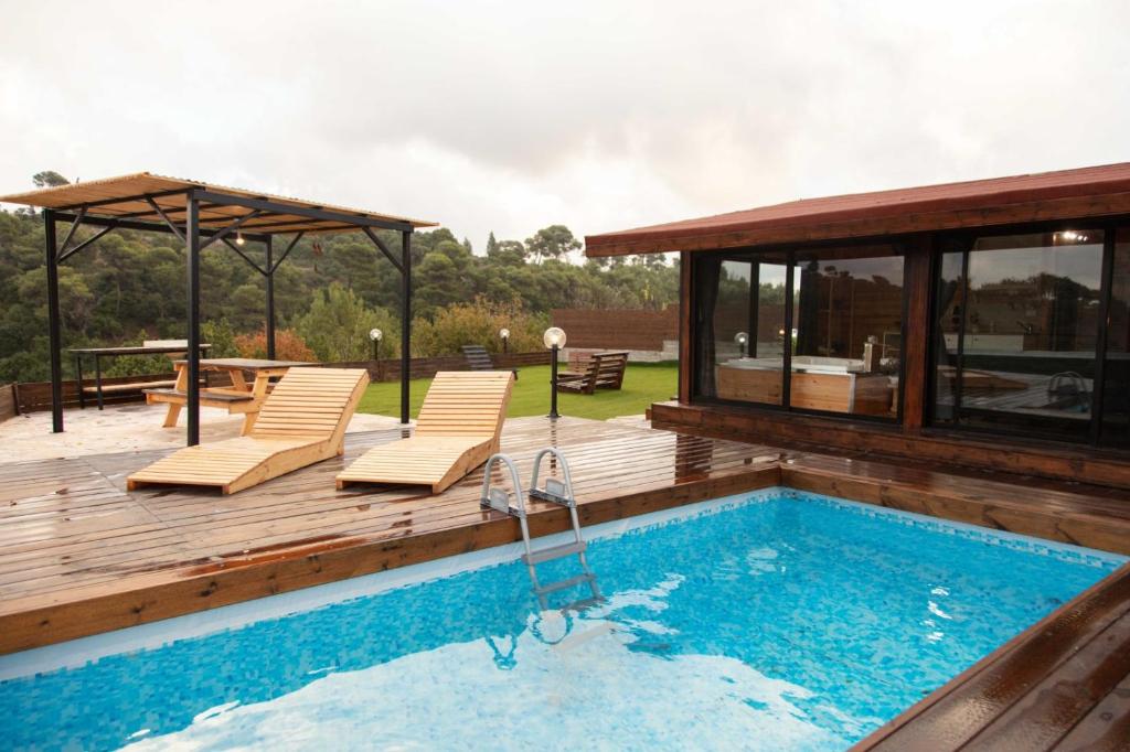 una terraza de madera con piscina y una casa en צימר המעיין en ‘Isfiyā