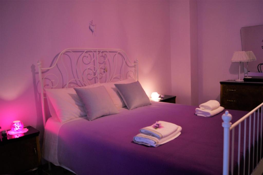 a purple bedroom with a white bed with towels on it at Ponte Rio in Pettorano sul Gizio