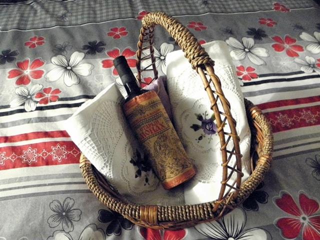 a basket with a bottle of wine and a book at Apartmani Nina in Sarajevo