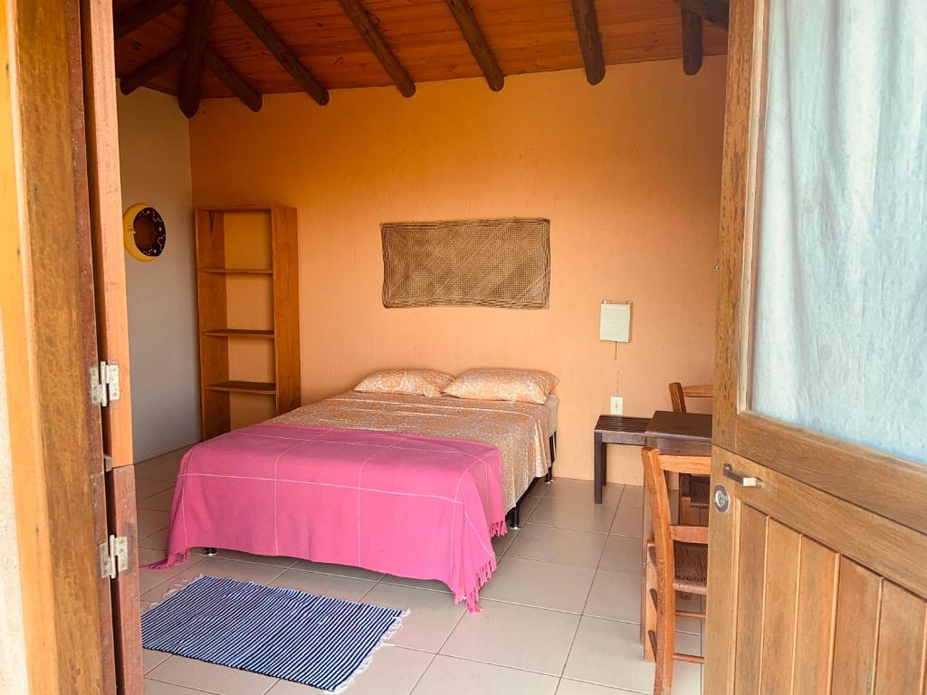 um quarto com uma cama com um cobertor rosa em Villa California na Praia do Rosa