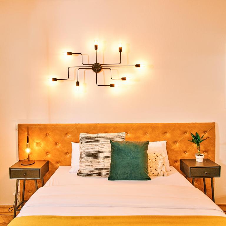 a bedroom with a bed with a chandelier above it at CAMŌ Boutique Apartments in Prague