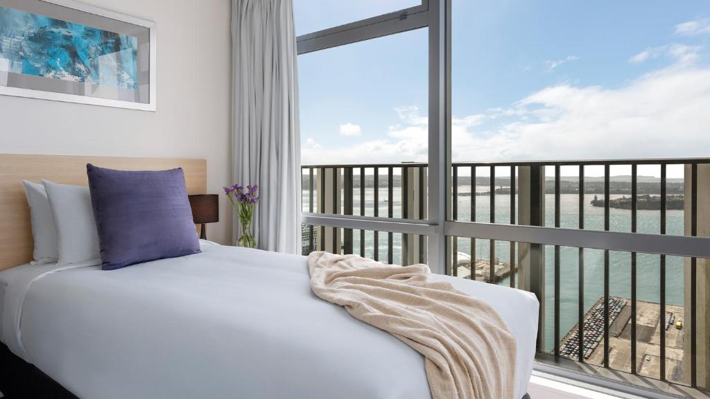 a bedroom with a bed and a large window at Auckland Harbour Suites in Auckland