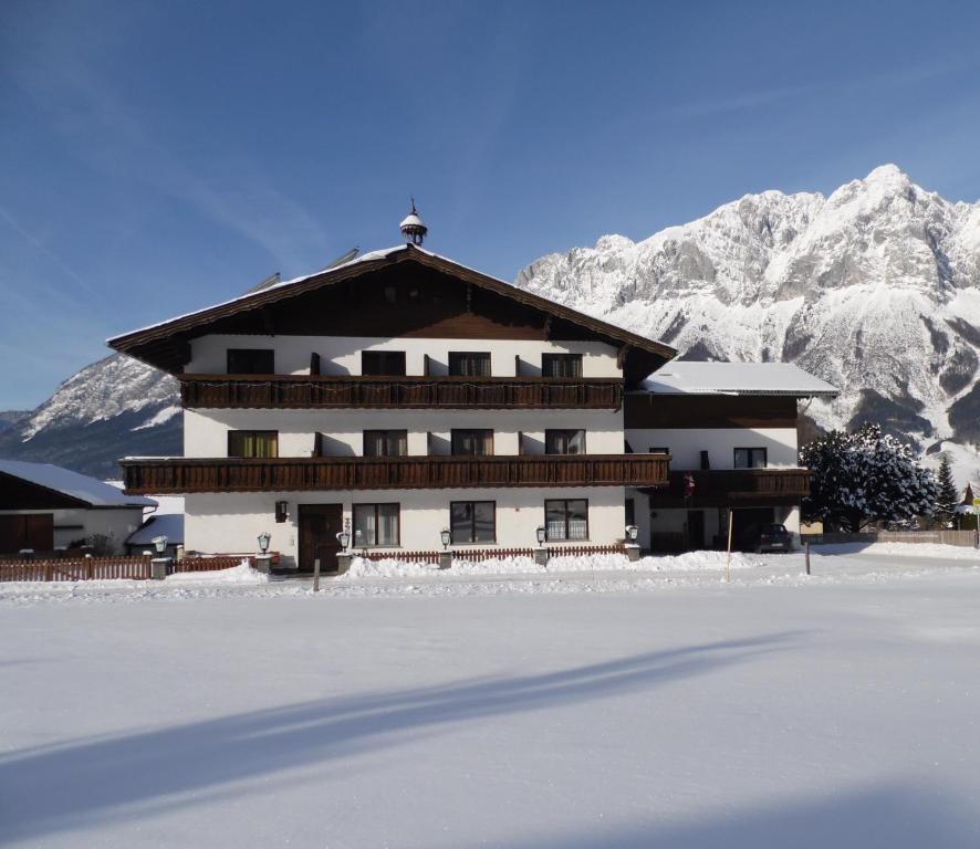 a building with snowy mountains in the background at Pension Tilly in Niederöblarn