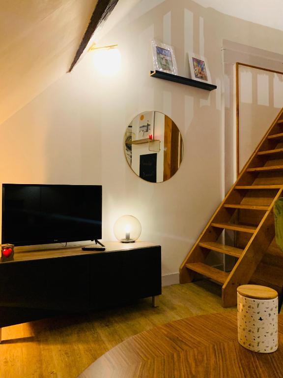 a living room with a tv and a staircase at La maison de Nina in Sens