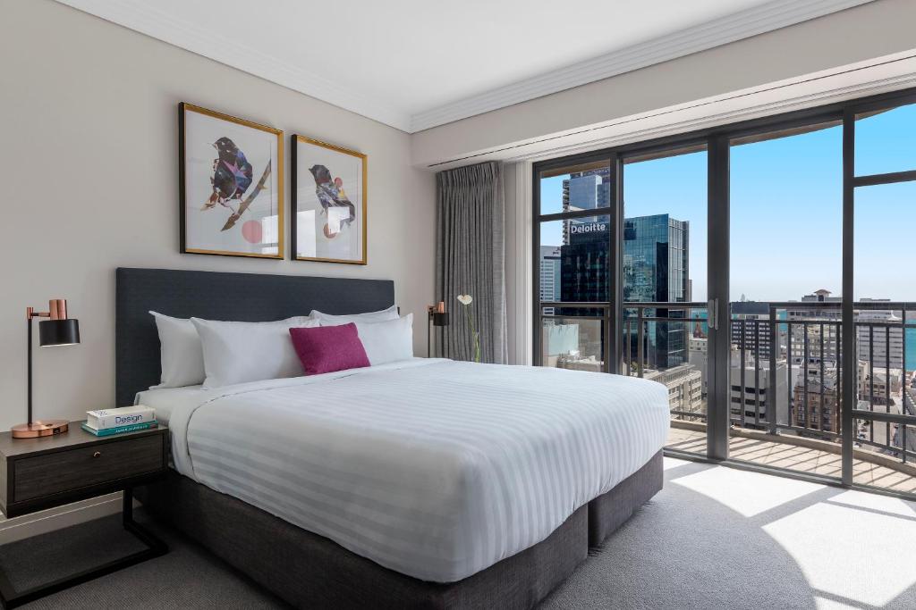 a bedroom with a large bed and a large window at Avani Metropolis Auckland Residences in Auckland