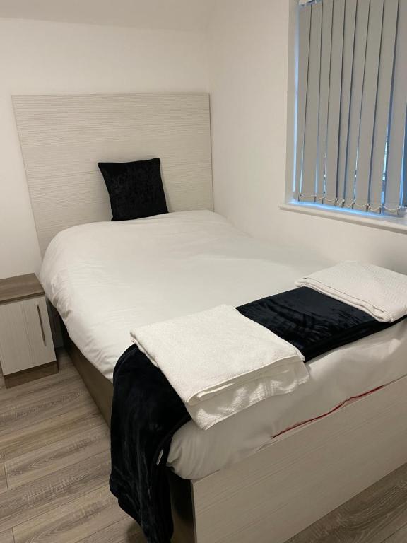 1 dormitorio con 1 cama con sábanas blancas y ventana en Luxury Lavish Studio Apartments LE1, en Leicester
