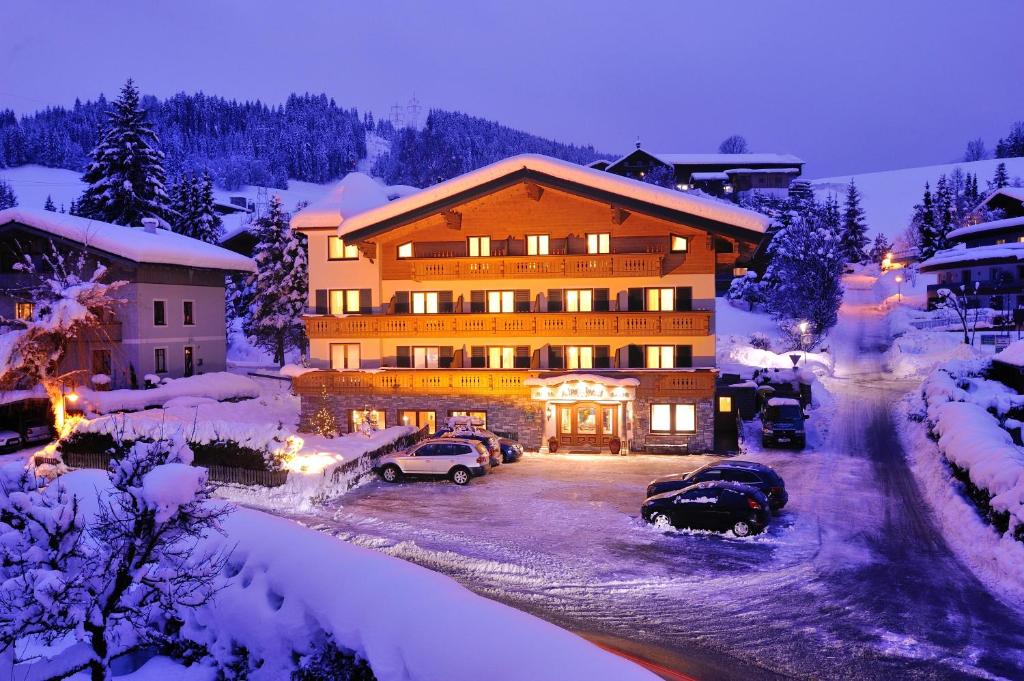 a building with cars parked in a parking lot in the snow at Hotel Garni Alpenland in Altenmarkt im Pongau