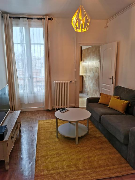 uma sala de estar com um sofá e uma mesa em Studio bien placé pour visiter Paris em Vincennes