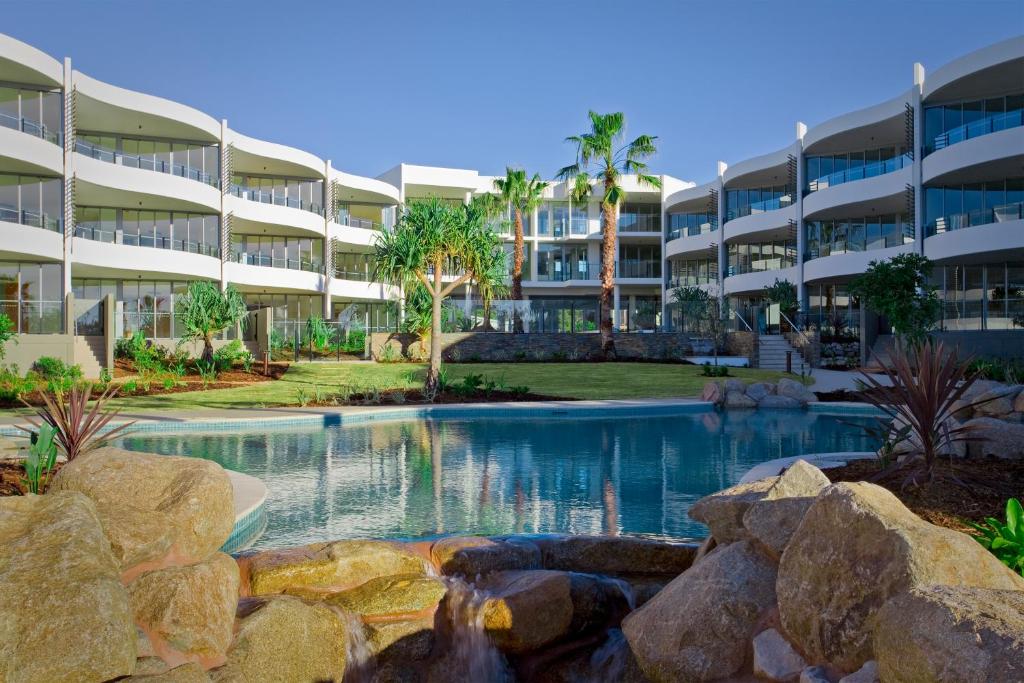 a swimming pool in front of a large apartment building at Cotton Beach Resort - Tweed Coast Holidays ® in Kingscliff