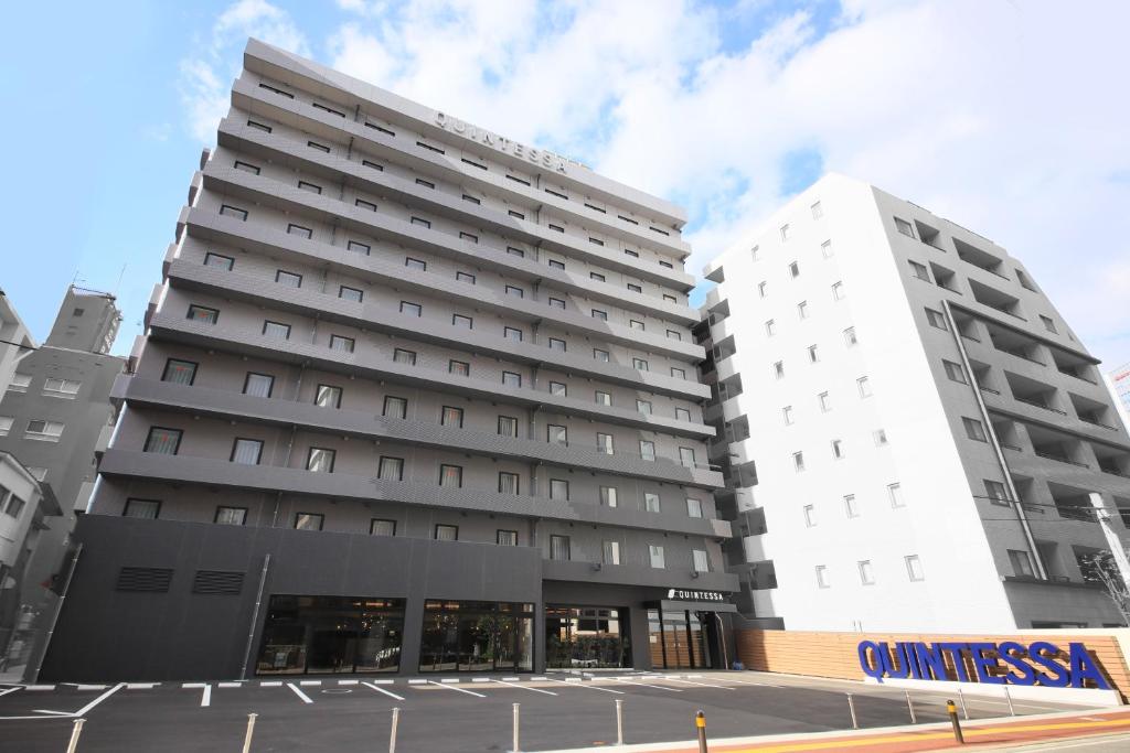 dois edifícios brancos altos ao lado de um parque de estacionamento em Quintessa Hotel Fukuoka Tenjin Minami em Fukuoka