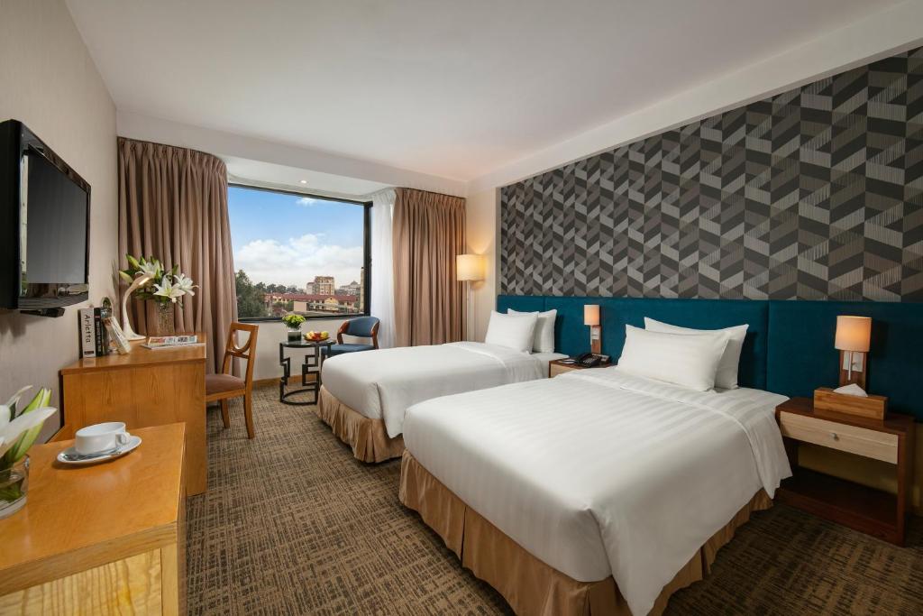 ハノイにあるラ カーサ ハノイ ホテルのベッド2台とテレビが備わるホテルルームです。