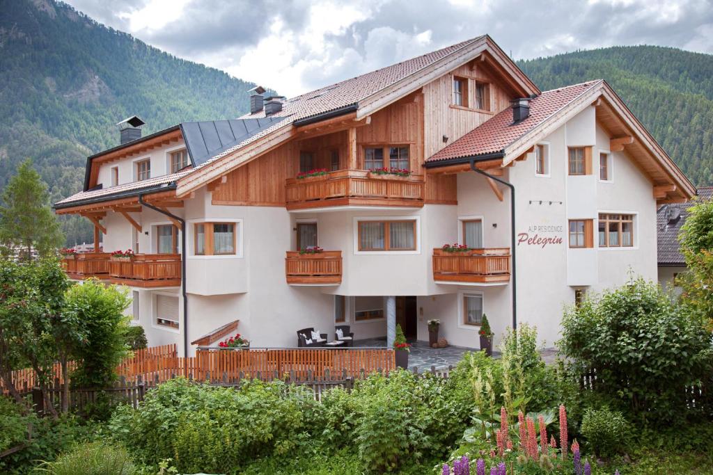 une grande maison avec balcon en bois dans les montagnes dans l'établissement Alp Residence Pelegrin, à San Vigilio Di Marebbe