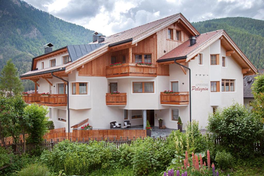 une grande maison avec des balcons en bois dans les montagnes dans l'établissement Alp Residence Pelegrin, à San Vigilio Di Marebbe