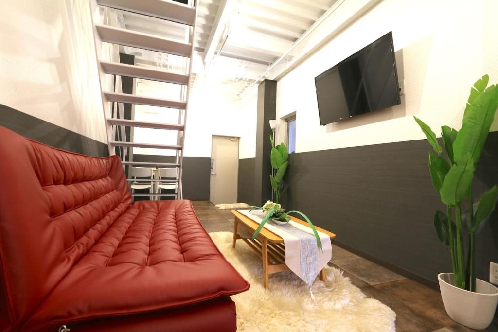 Il comprend un salon doté d'un canapé rouge et d'une télévision à écran plat. dans l'établissement EK1 Elizabeth Garden Kuromon, à Osaka
