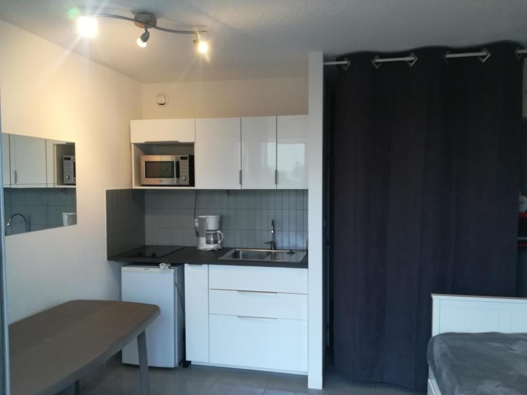 a small kitchen with white cabinets and a sink at Studio la grande motte, parking in La Grande-Motte