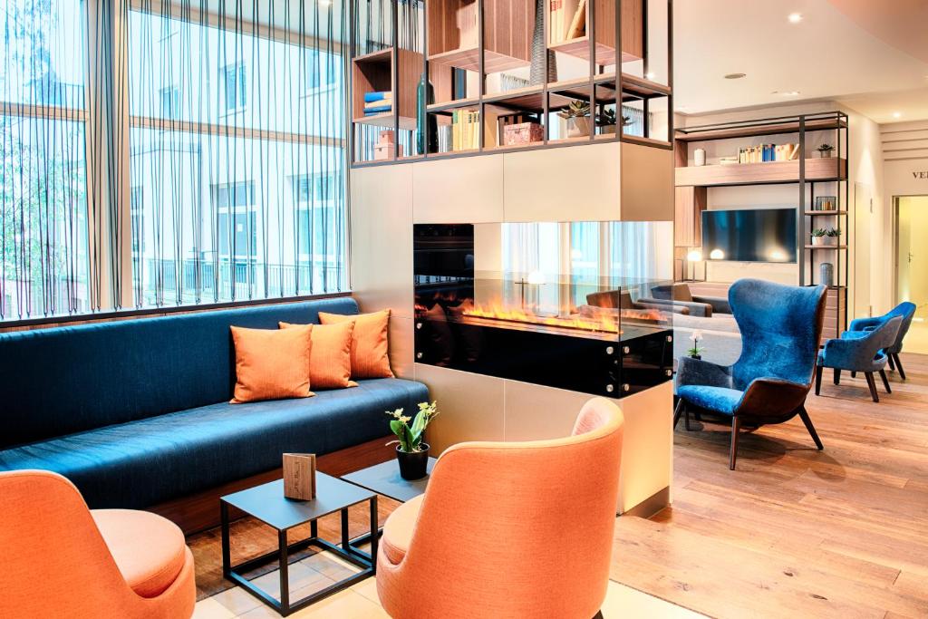 マールブルク・アン・デア・ラーンにあるウェルカム ホテル マールブルクのリビングルーム(青いソファ、オレンジの椅子付)