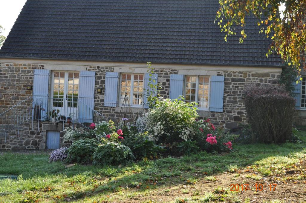 uma casa de tijolos com janelas azuis e flores no quintal em Ma maison bleue em Saint-Brice-sous-Rânes