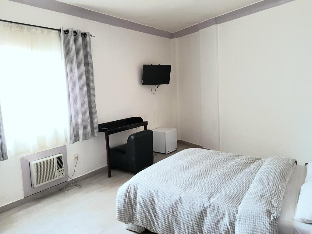 a bedroom with a bed and a chair and a television at Hotel du Golfe de Guinée in Conakry