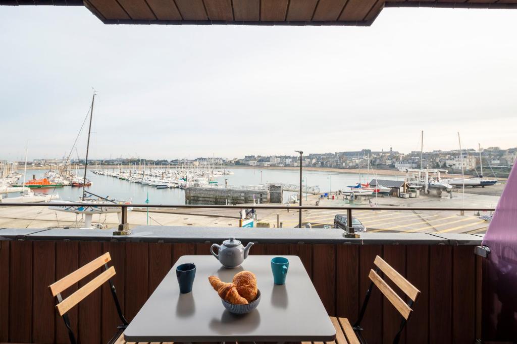 a table with bread and a vase on it with a view of a harbor at La Cabine by Cocoonr in Saint Malo