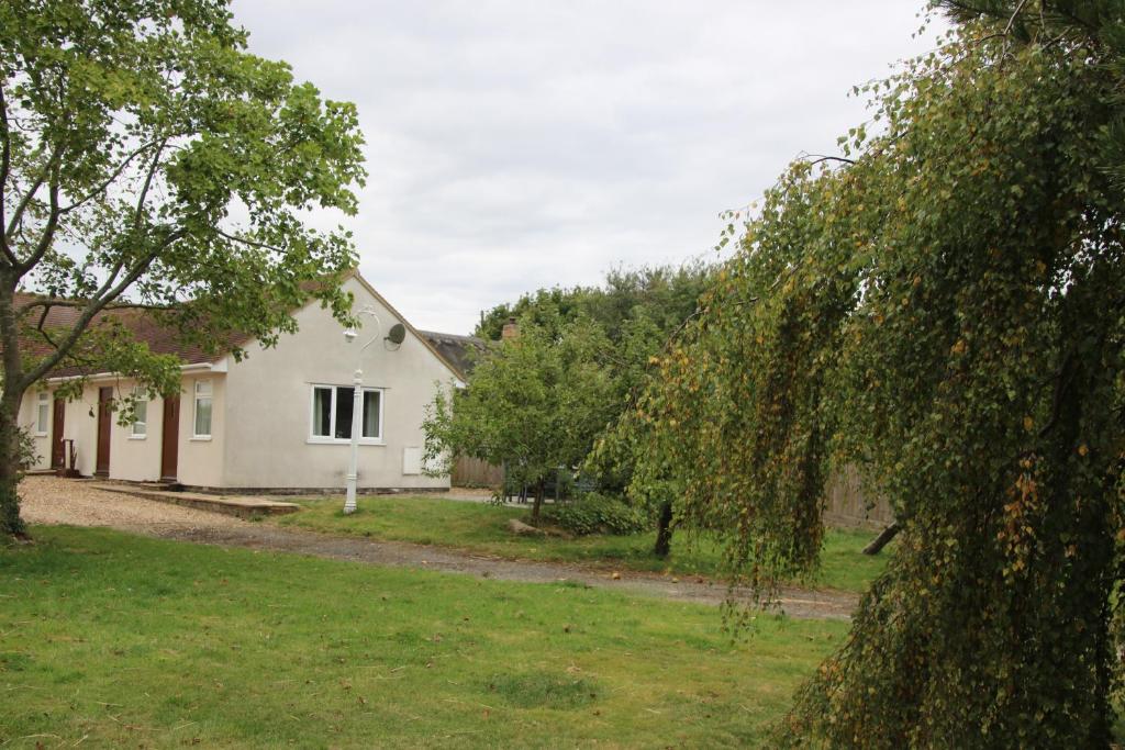 une maison blanche avec des arbres devant elle dans l'établissement The Stables B&B @ Pear Tree Cottage, à Winslow