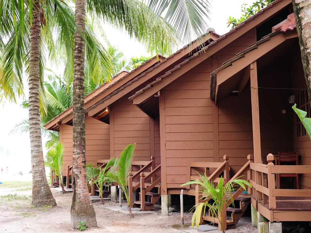 a wooden house with palm trees in front of it at Redang Paradise Resort in Redang Island