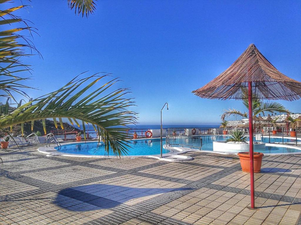 ein Resort mit einem Pool und einem Sonnenschirm in der Unterkunft Guanabara park in Puerto Rico de Gran Canaria