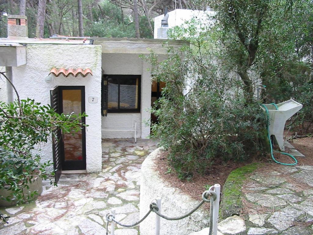 una pequeña casa blanca con una puerta y un árbol en Appartamento La Perla a soli 100m dal mare a Marina di Castagneto en Marina di Castagneto Carducci