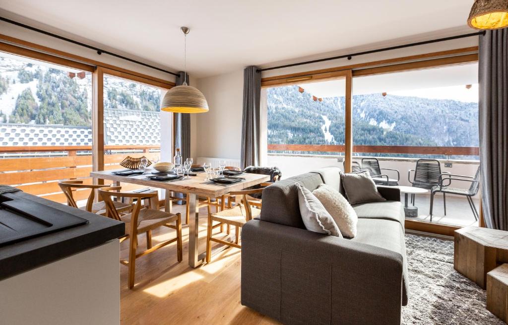 sala de estar con mesa, sillas y ventana grande en TERRESENS - Le Saphir, en Vaujany