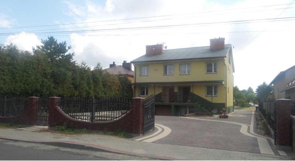 a yellow house with a fence in front of it at Pokoje Jasionka Zaczernie in Trzebownisko