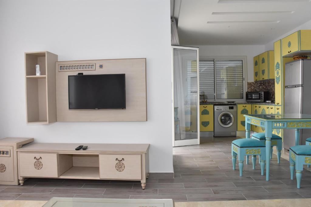 a living room with a table and a tv on a wall at Arabesque Style - 2 appartements in Kelibia