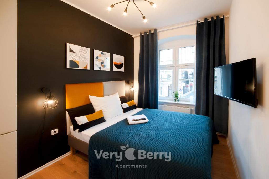 a small bedroom with a bed with a blue blanket at Very Berry - Glogowska 35a - MTP Apartments - self check in 24h in Poznań