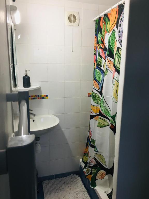 a bathroom with a sink and a shower curtain at Le Tendance : Studio avec Jardin in Courcouronnes