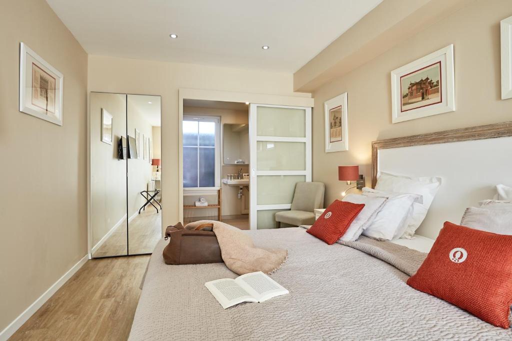 a bedroom with a large bed with red pillows at Les Villas d'Arromanches, Teritoria in Arromanches-les-Bains