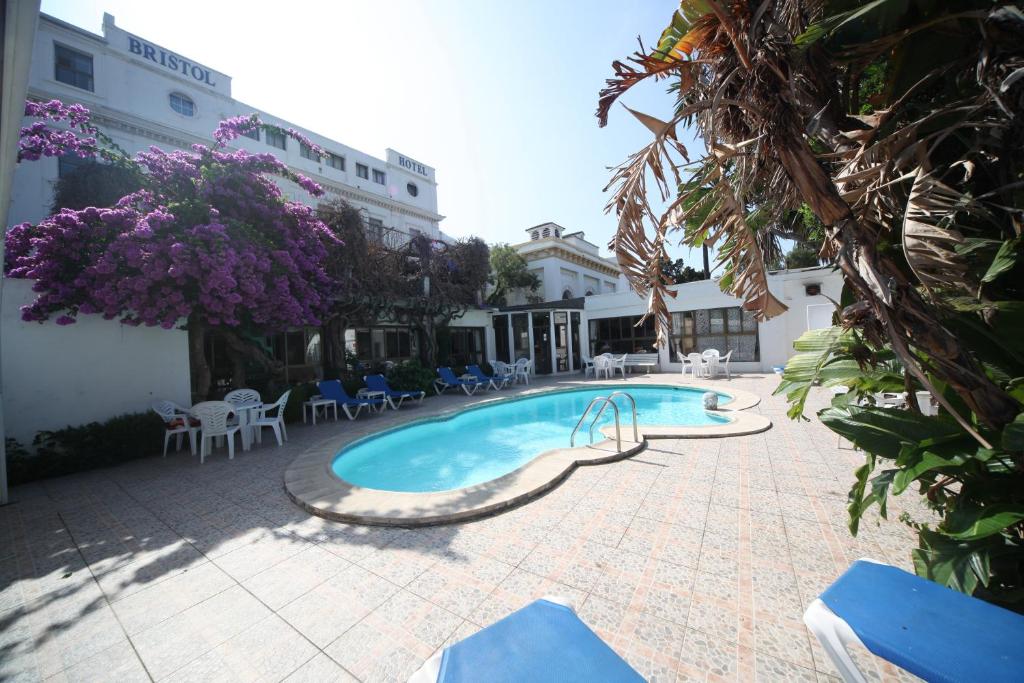 a swimming pool with chairs and purple flowers next to a building at Bristol Hotel in Gibraltar