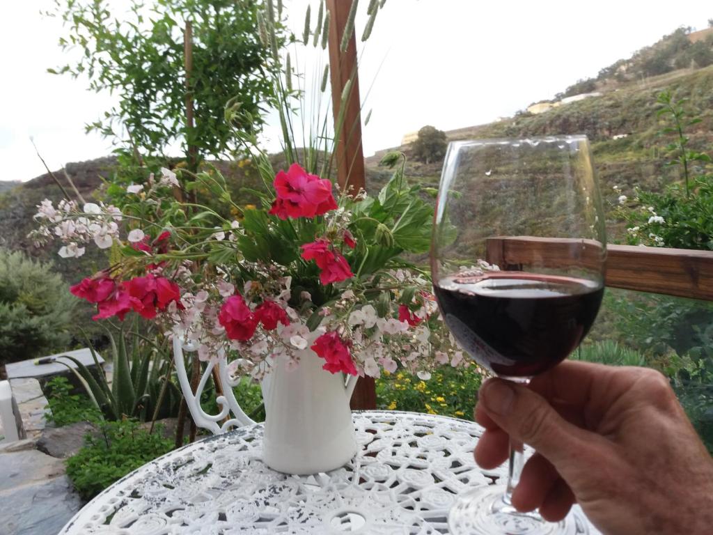 a person holding a glass of wine on a table with flowers at La cueva de Ángel B&B in Firgas